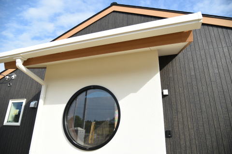 黒と白のツートンカラーの丸窓切妻屋根の平屋