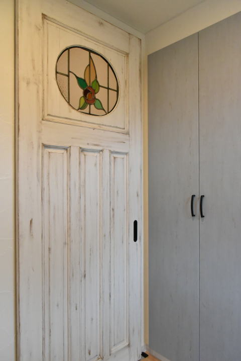 水色の玄関収納とアンティーク加工塗装のステンドグラス引き戸