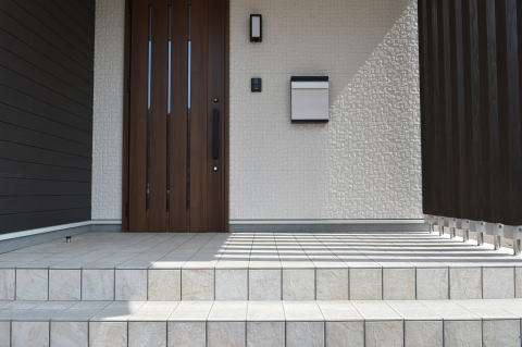 白いタイルと茶色のドアのある玄関ポーチ