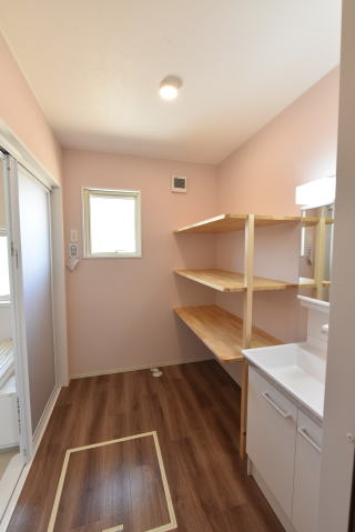ピンクの壁紙と茶色の床の洗面脱衣室