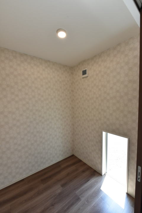 茶色い床と丸い模様の壁紙の洋室