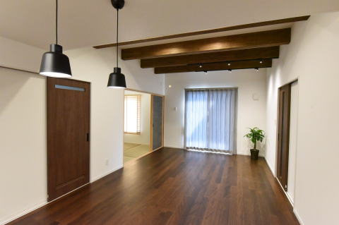和室が隣にある茶色の床と梁あらわし天井のダイニングキッチン