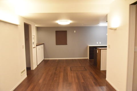 濃い茶色の床とロールスクリーンのLDK　白と茶色の作り付け家具