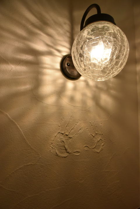 丸いクラックガラスの壁灯と塗り壁に付けられた手形