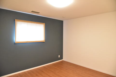 茶色の床とブルーのアクセントクロスの洋室