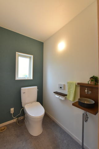 グレーの床とグリーンのアクセントクロスのトイレ