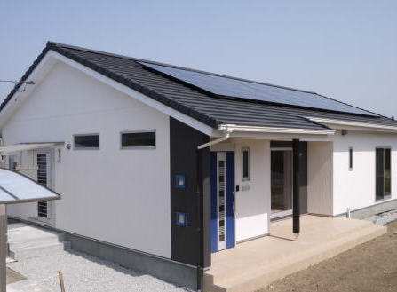 太陽光発電システムと広いタイルテラスのある切妻屋根の平屋