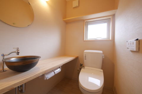 茶色と黒の手洗い器と木製カウンターのある洋式トイレ