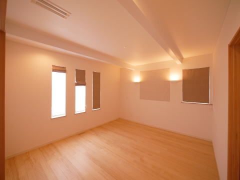 白い梁あらわし天井とアクセントタイルのある洋室
