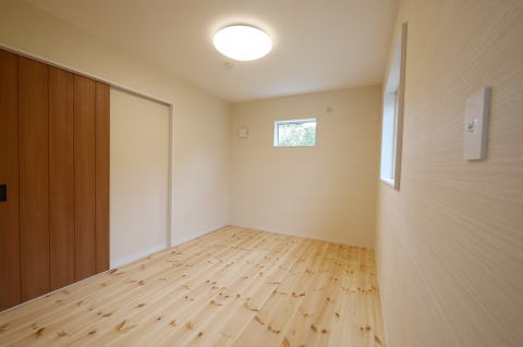 茶色の引き戸とパイン無垢床材の洋室