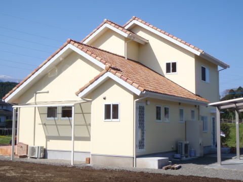 オレンジの瓦屋根とクリーム色の外壁の2階建て南欧風の家外観