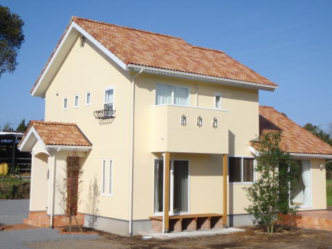 オレンジの瓦屋根とクリーム色の外壁の2階建て南欧風の家外観