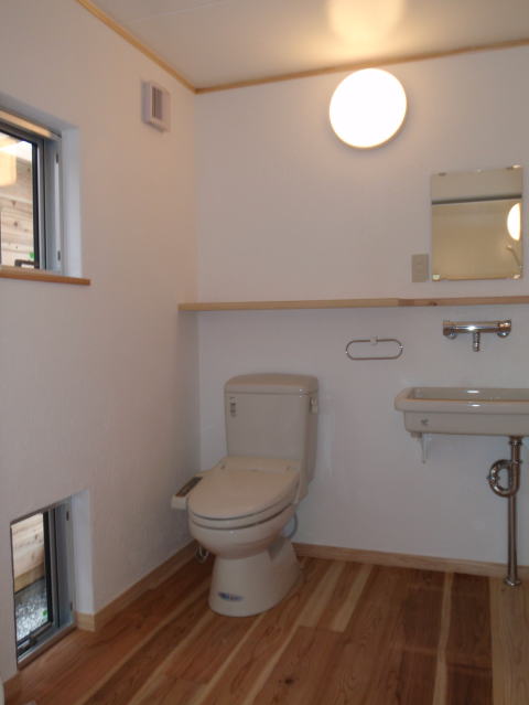 丸い壁灯と洗面台ののある洋式トイレ