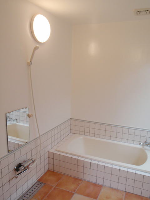 テラコッタタイルと白い壁と丸い照明のあるバスルーム