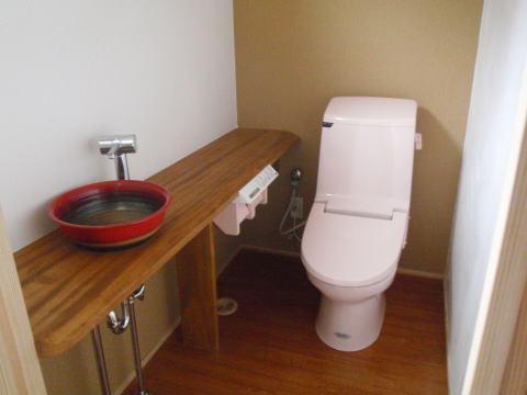 赤い手洗い器のあるピンクの洋式トイレ
