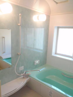 グリーンの浴槽と薄いブルーのアクセント壁のあるバスルーム