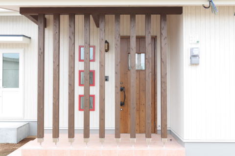 赤枠窓と茶色塗装のポーチ柱のある玄関